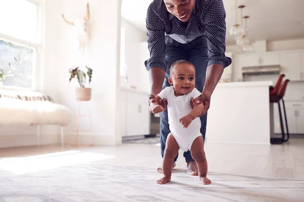 Father Encouraging Smiling Baby Daughter Take First Steps Walk Home — Stock Photo, Image