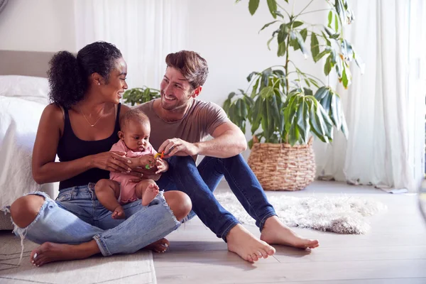 ベッドルームで床に座って赤ちゃんの娘と遊ぶ愛する両親 — ストック写真