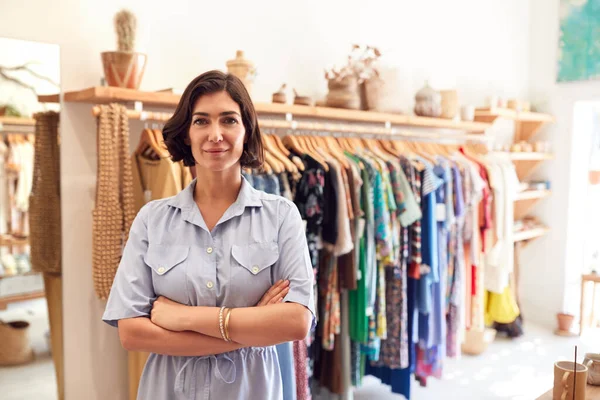 レールの上で服の前に立つファッションストアの笑顔の女性オーナーの肖像 — ストック写真