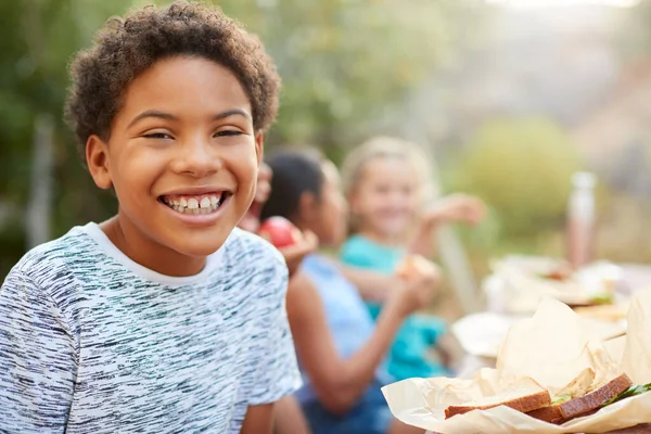 Portret Chłopca Przyjaciółmi Jedzącego Zdrowy Piknik Przy Stole Świeżym Powietrzu — Zdjęcie stockowe