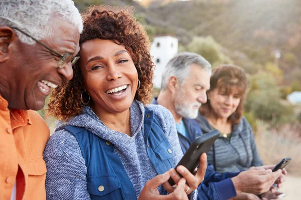 Seniorengruppe Wandert Auf Dem Land Und Schaut Gemeinsam Auf Mobiltelefone — Stockfoto