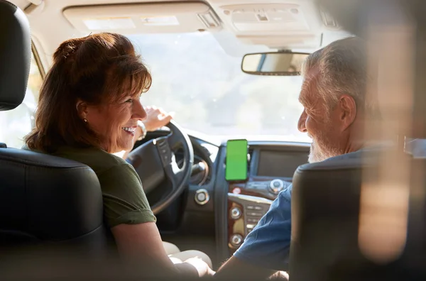 携帯電話でサットナビを使用して田舎をドライブするシニアヒスパニックカップル — ストック写真