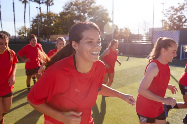 アウトドアアストロ芝ピッチでサッカーの試合のためのトレーニング中に女子サッカーチームを実行 — ストック写真