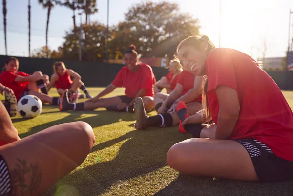 女子足球队在室外露天草地球场足球比赛训练中的伸展动作 — 图库照片