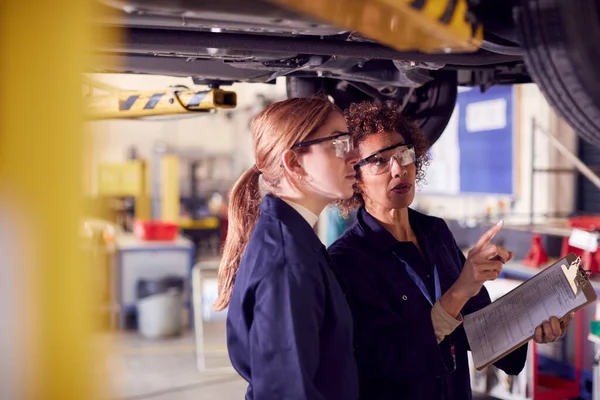 Vrouwelijke Leraar Met Student Zoek Onder Auto Hydraulische Ramp Auto — Stockfoto