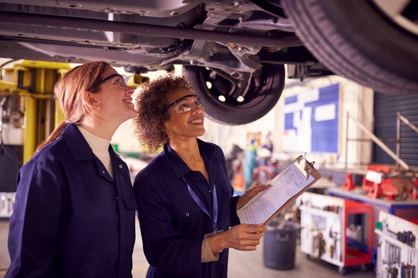 Tutorin Mit Studentin Sucht Unter Auto Auf Hydraulikrampe Auf Auto — Stockfoto