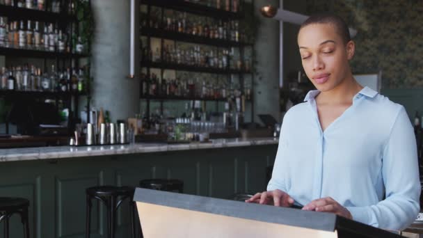 サービスの前に予約を確認してカウンターに立っているレストランバーの女性オーナーの肖像 スローモーションで撮影 — ストック動画