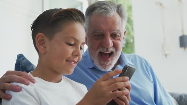 Nieto Hispano Que Muestra Abuelo Cómo Usar Teléfono Móvil Casa — Vídeos de Stock