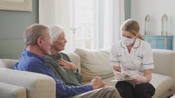 Kvinnlig Läkare Bär Ansiktsmask Gör Hem Besök Hos Senior Par — Stockvideo