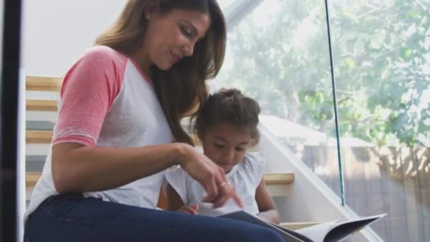 Madre Hija Hispanas Sentadas Escalera Moderno Libro Lectura Casera Juntas — Vídeos de Stock