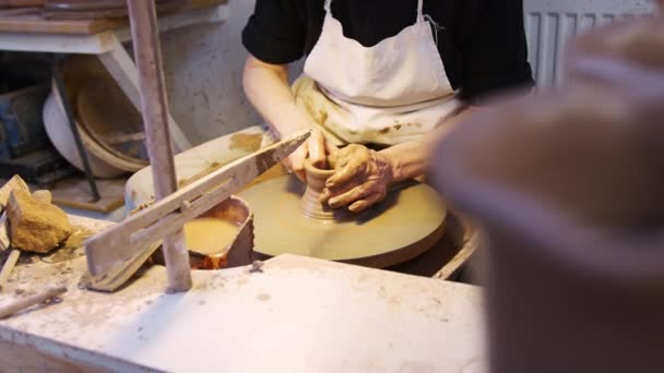 陶芸スタジオの陶芸ホイールに鍋のための男性のポッターの形の粘土のクローズアップ — ストック動画