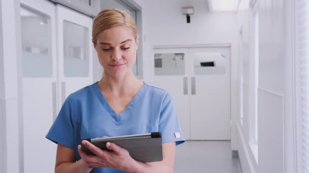 Hastane Koridorunda Dijital Tablet Kullanarak Önlük Giyen Gülümseyen Kadın Doktor — Stok video