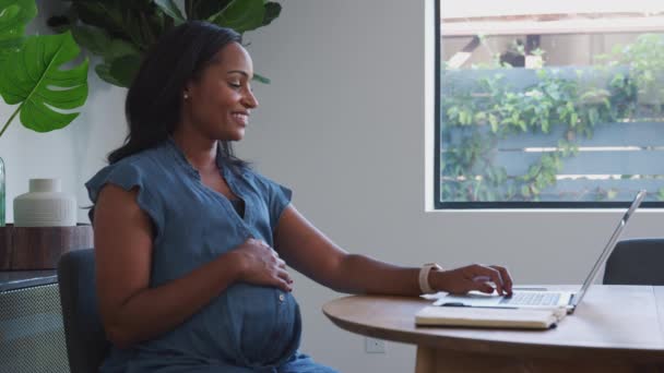 집에서 일하는 테이블에서 랩탑을 사용하여 아프리카계 미국인 임신부를 미소짓는 동작으로 — 비디오