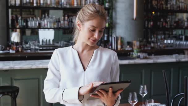デジタルタブレットを使用してカウンターに立っているレストランバーの女性オーナーの肖像 スローモーションで撮影 — ストック動画