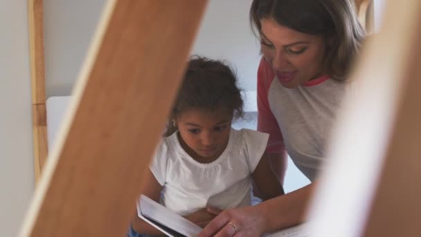 西班牙裔母亲和女儿一起坐在女孩的双层床上看书 动作缓慢 — 图库视频影像