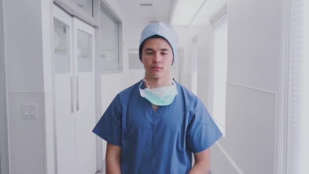 病院の廊下でスクラブやマスクを身に着けている男性外科医の肖像 スローモーションで撮影 — ストック動画