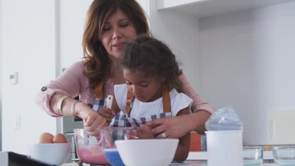 ヒスパニック系の祖母と孫娘が一緒にケーキを焼くために食材を混合キッチンで楽しみを持っています スローモーションで撮影 — ストック動画