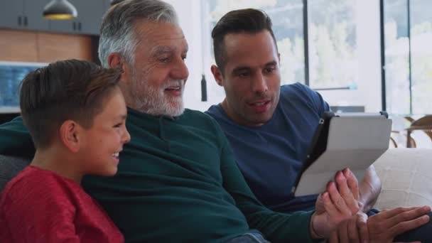 多代男性惊慌失措的家庭坐在家里的沙发上 一起在数码平板电脑上看电影 慢镜头拍摄 — 图库视频影像