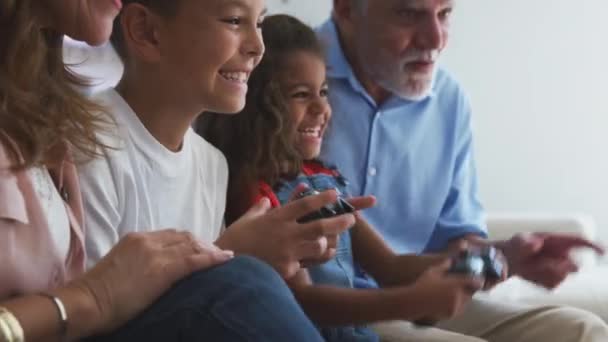 与孙子孙女一起在家里玩电子游戏坐在沙发上的西班牙裔祖父母 慢镜头 — 图库视频影像