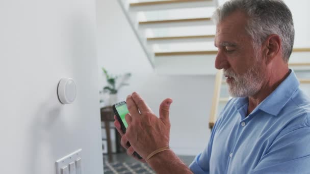 Senior Latynos Pomocą Aplikacji Telefonie Komórkowym Aby Dostosować Cyfrowy Termostat — Wideo stockowe