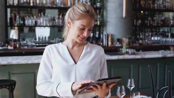 デジタルタブレットを使用してカウンターに立っているレストランバーの女性オーナーの肖像 スローモーションで撮影 — ストック動画