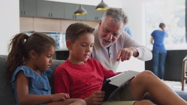 Dziadek Grający Gry Wideo Wnukami Tablecie Cyfrowym Salonie Domu Nakręcony — Wideo stockowe