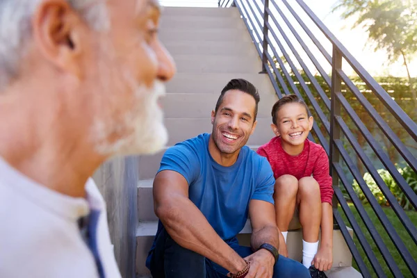 Sonriente Familia Hispana Masculina Multigeneracional Sentada Pasos Jardín Hablando Juntos —  Fotos de Stock
