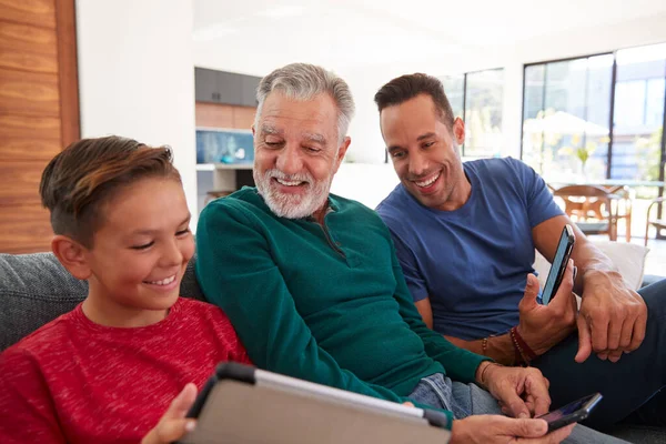 Multi Generation Male Hispanic Family Sitting Sofa Home Using Mobile — 스톡 사진