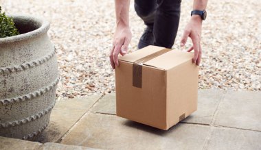 Close Up Of Delivery Driver Putting Package On Doorstep Outside House clipart
