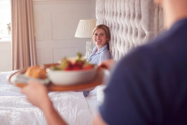 結婚記念日を祝うためにベッドで女性の朝食をもたらす男 — ストック写真