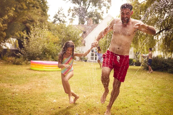Father Daughter Run Water Garden Sprinkler Having Fun Wearing Swimming — Stock Photo, Image