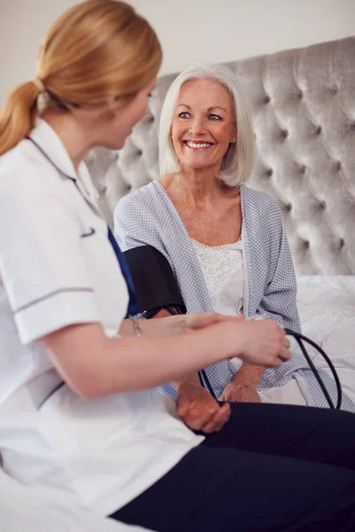 Női Orvos Teszi Otthoni Látogatás Senior Hálószobában Vérnyomás Ellenőrzése — Stock Fotó