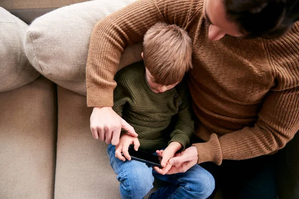 爸爸和儿子在家里沙发上玩手机游戏玩得开心 — 图库照片