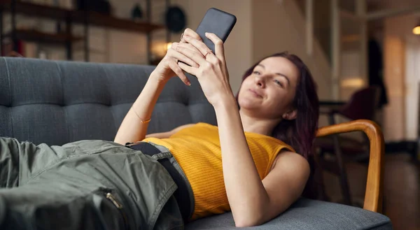 Ung Kvinna Som Ligger Soffan Hemma Tittar Mobilmeddelanden Och Sociala — Stockfoto