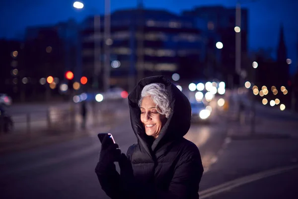 Зрелая Женщина Городской Улице Ночью Заказывая Такси Помощью Мобильного Телефона — стоковое фото