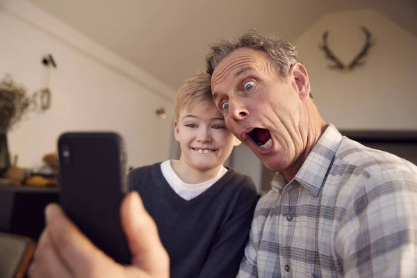 Neto Com Avô Puxando Rostos Tirando Selfie Telefone Celular Casa — Fotografia de Stock