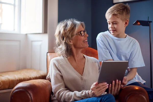 Barnbarn Med Mormor Sitter Stolen Och Spelar Digital Surfplatta Hemma — Stockfoto