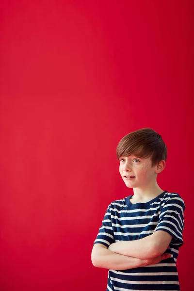 Портрет Молодого Хлопчика Складеними Руками Проти Червоного Фону Студії Усміхаючись — стокове фото