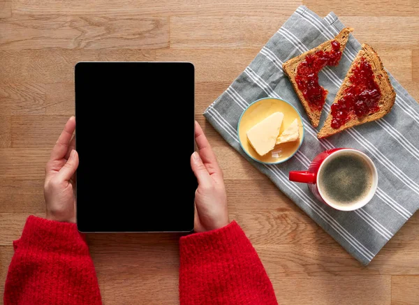 Overhead Flat Lay Of Woman With Digital Tablet On Table Laid For Breakfast With Croissant And Coffee