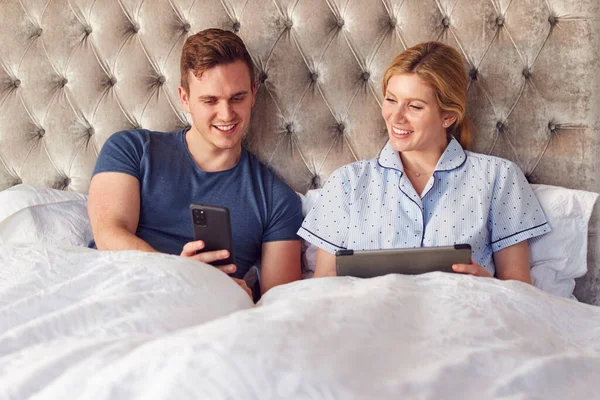 Covid Lockdown中にデジタルタブレットと携帯電話を使用して分離ベッドで自宅でカップル — ストック写真