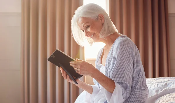 Glimlachende Senior Vrouw Zitten Rand Van Bed Zoek Naar Foto — Stockfoto