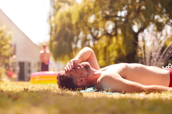 Mature Man Lying Grass Sunbathing Home Children Play Pool — Stock Photo, Image