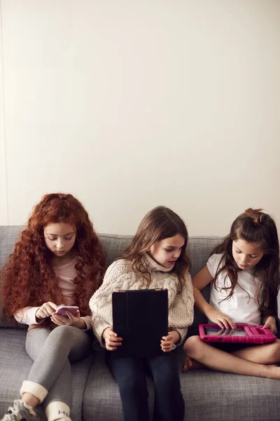 Grupa Dziewczyn Przyjaciółmi Siedzi Kanapie Domu Grając Tablecie Cyfrowym Telefony — Zdjęcie stockowe