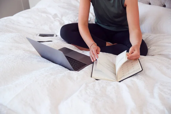 自宅から仕事でノートパソコンと日記をベッドに座っているビジネスマンのクローズアップ — ストック写真
