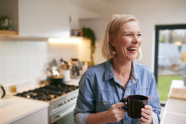 Γελώντας Ώριμη Γυναίκα Στο Σπίτι Στην Κουζίνα Πίνοντας Καφέ — Φωτογραφία Αρχείου