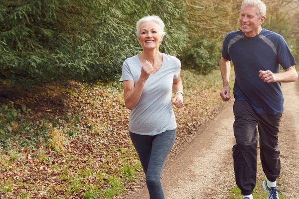 Senior Couple Exercising In Autumn Countryside During Covid 19 Lockdown