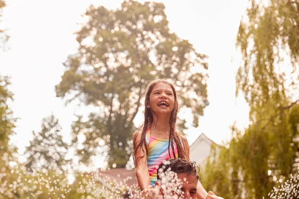 Vader Draagt Dochter Door Water Van Tuin Sproeier Hebben Plezier — Stockfoto