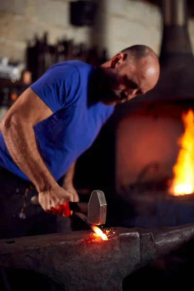 Blazing Forgeを背景にしたAnvilでの男性鍛冶屋の金属加工 — ストック写真