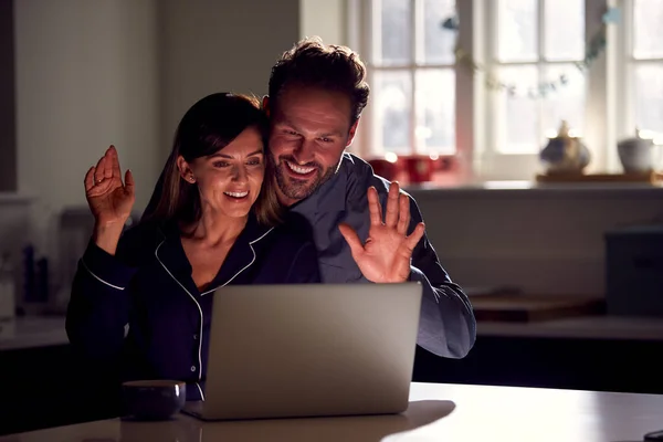 Couple Wearing Pyjamas Sitting Kitchen Night Using Laptop Video Call — Zdjęcie stockowe