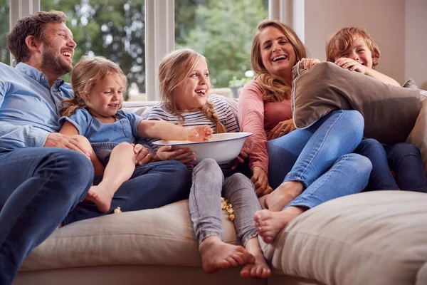 Rodzina Siedzi Kanapie Domu Śmiejąc Się Oglądając Telewizję Popcornem — Zdjęcie stockowe